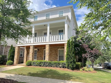 View of front facade with a balcony, a front yard, and stone siding
