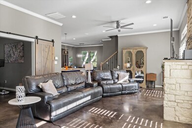 Living area featuring a barn door, concrete floors, ornamental molding, a ceiling fan, and recessed lighting