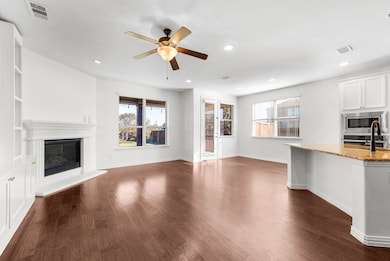 Unfurnished living room featuring healthy amount of natural light, a glass covered fireplace, dark wood-type flooring, recessed lighting, and ceiling fan