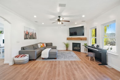 Living area featuring crown molding, arched walkways, light wood finished floors, recessed lighting, and a fireplace