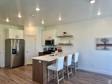 The modern kitchen boasts a peninsula of sleek countertops, appliances with stainless steel finishes, modern open shelves, and dark wood finished floors