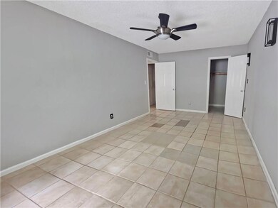 Unfurnished bedroom with a textured ceiling, light tile patterned floors, a ceiling fan, and a closet