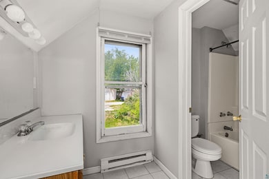 Full bath with baseboard heating, vanity, toilet, tile patterned floors, and vaulted ceiling