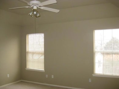 Carpeted empty room featuring baseboards and a ceiling fan