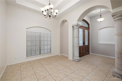 Tiled entrance foyer featuring decorative columns and an inviting chandelier
