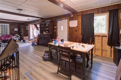 Dining area with wooden walls, wood finished floors, and a paneled ceiling
