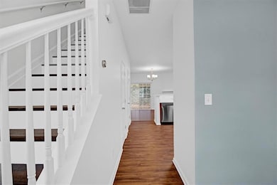 Hallway with stairway, baseboards, visible vents, 