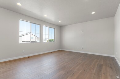 Empty room with light wood-style flooring and recessed lighting