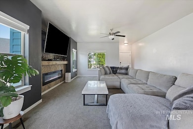 Carpeted living area with a ceiling fan and a glass covered fireplace