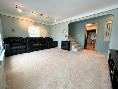 Living area with light colored carpet, rail lighting, and stairs