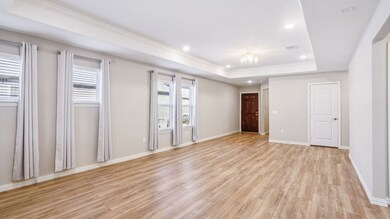Empty room featuring a tray ceiling, crown molding, recessed lighting, and light wood-style floors
