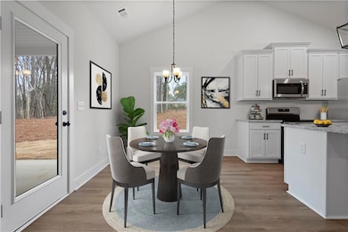 Dining space with vaulted ceiling, a chandelier, wood finished floors, and baseboards