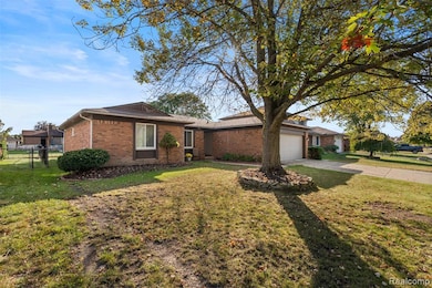 Ranch-style house featuring concrete driveway, an attached garage, and brick siding