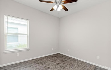Unfurnished room featuring baseboards, wood finished floors, and ceiling fan