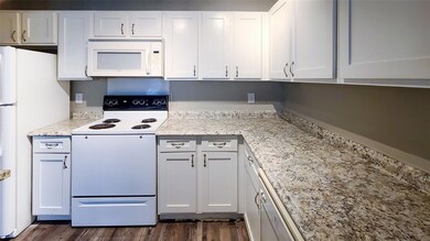 Kitchen featuring light stone counters, dark wood-