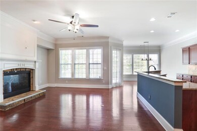 Living room with dark wood-style floors, visible vents, a glass covered fireplace, baseboards, and ceiling fan