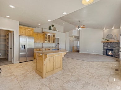 Kitchen with stainless steel fridge, glass insert cabinets, a fireplace, a breakfast bar, and light brown cabinetry