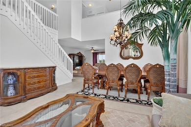 Dining space featuring a chandelier, light tile patterned floors, a towering ceiling, a ceiling fan, and stairs