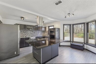 Kitchen featuring tasteful backsplash, modern cabinets, island exhaust hood, stainless steel appliances, and light wood-style floors
