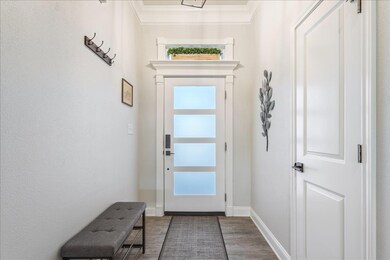 Doorway with wood finished floors and crown moldi