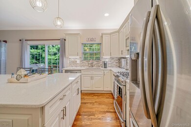 Kitchen with appliances with stainless steel finishes, backsplash, ornamental molding, light stone counters, and light wood-type flooring