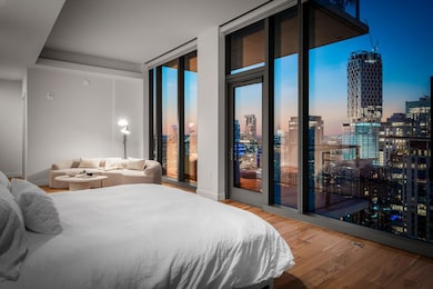 Bedroom with light wood-style flooring, a skyline view, access to outside, and floor to ceiling windows