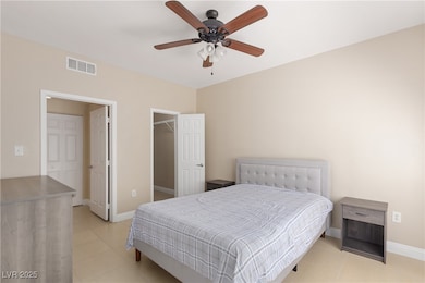 Bedroom with a walk in closet, light tile patterned floors, and ceiling fan