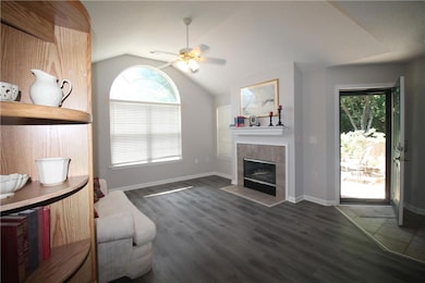 Living area with plenty of natural light, lofted ceiling, a tiled fireplace, and luxury vinyl flooring