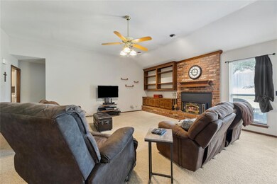 Living room featuring ceiling fan, brick wall, lig