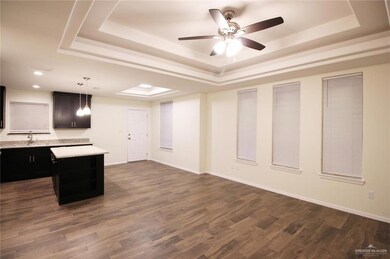 Kitchen with a raised ceiling, light countertops, a kitchen island, a ceiling fan, and recessed lighting