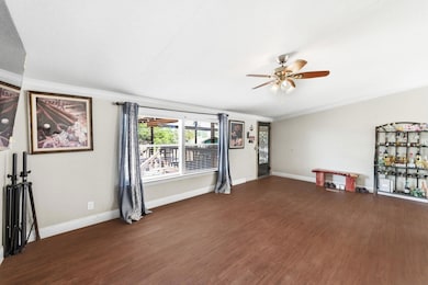 Unfurnished living room with ornamental molding, wood finished floors, and a ceiling fan