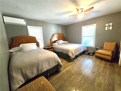 Bedroom with laminate flooring, a wall unit AC, and a ceiling fan