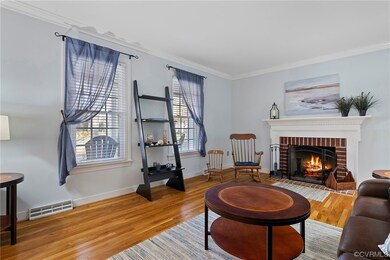 Living room with a brick fireplace, light hardwood