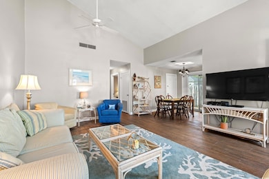 Living room featuring ceiling fan, high vaulted ceiling, wood-type flooring, and a chandelier