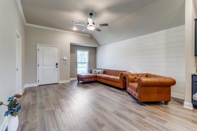 Living room with hardwood / wood-style flooring, ornamental molding, ceiling fan, and vaulted ceiling