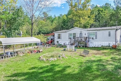 Rear view of property featuring cooling unit, a carport, and a yard