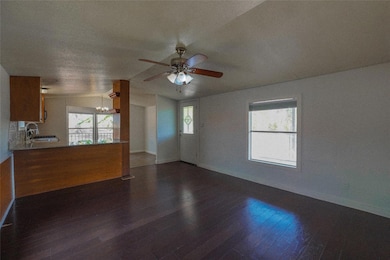Unfurnished living room with dark wood finished floors, a chandelier, vaulted ceiling, and a ceiling fan