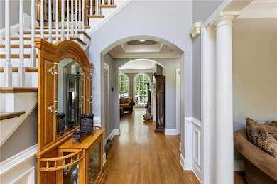 Hall with wood finished floors, ornamental molding, stairs, and arched walkways
