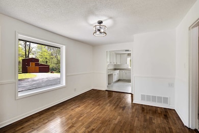 Unfurnished dining area featuring visible vents, baseboards, a textured ceiling, and dark wood finished floors