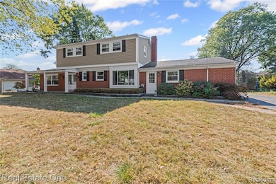 Colonial house featuring brick siding, a front yard, and a chimney