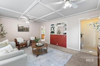 Living room featuring coffered ceiling, a ceiling fan, light colored carpet, and beamed ceiling