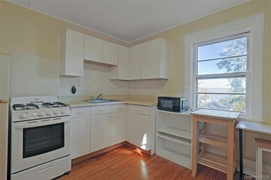 Kitchen with crown molding, white gas range oven, light wood finished floors, white cabinets, and light countertops