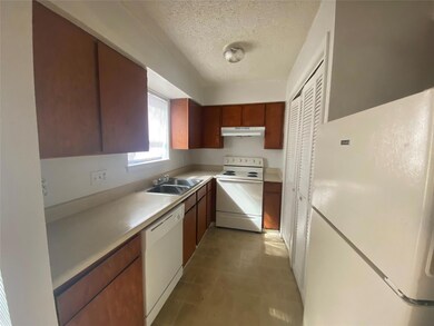 Kitchen featuring white appliances, a textured ceiling, light countertops, under cabinet range hood, and light tile patterned flooring