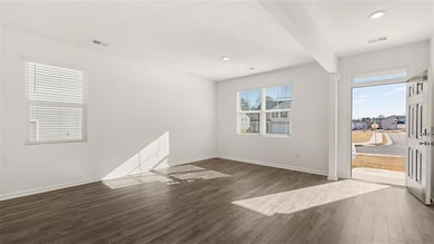 Unfurnished room with dark wood-style flooring and beam ceiling