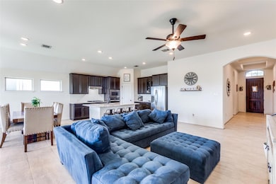 Living area featuring arched walkways, a ceiling fan, light tile patterned floors, and recessed lighting