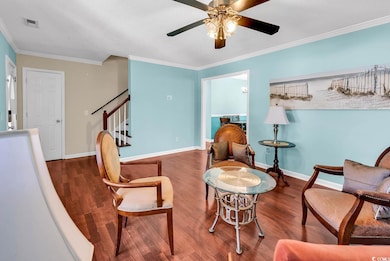 Living area with ornamental molding, a ceiling fan, wood finished floors, stairs, and baseboards
