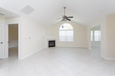 Unfurnished living room with plenty of natural light, a ceiling fan, a glass covered fireplace, vaulted ceiling, and light tile patterned floors