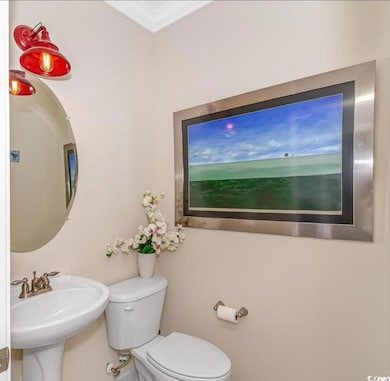 Half bath with a sink, toilet, and crown molding