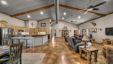 Living area with high vaulted ceiling, concrete flooring, beamed ceiling, and a ceiling fan