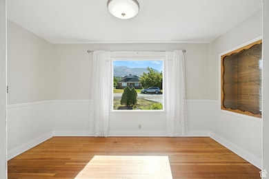 Dining room with hardwood floors and wainscoting. Features large east-facing windows.